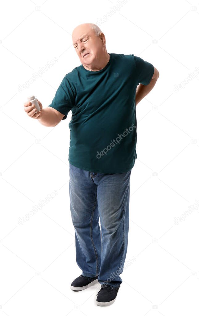 Senior man with bottle of pills suffering from back pain on white background