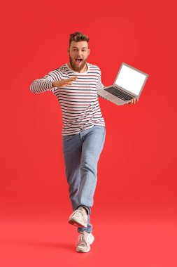 Dizüstü bilgisayarı renkli havalı dans eden genç adam.