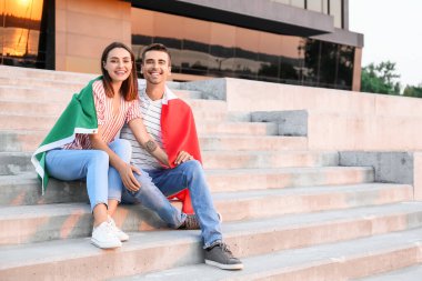 Açık havada İtalyan bayrağı taşıyan genç çift