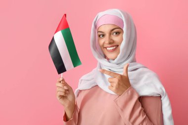 Geleneksel giyinmiş genç bir kadın ve arka planında BAE bayrağı var.