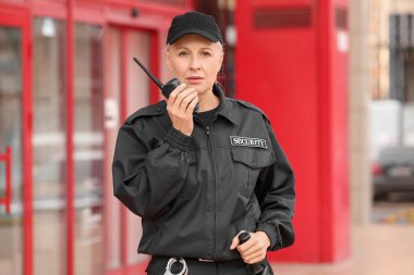 Dışarıda radyo vericisi olan kadın güvenlik görevlisi.