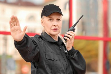 Bayan güvenlik görevlisi dışarıda jest yapıyor.