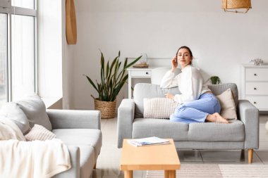 Evdeki kanepede dinlenen güzel genç bir kadın.