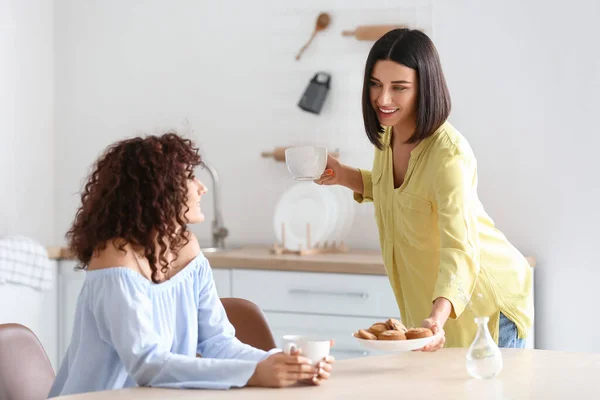 Young Woman Holding Cup Giving Plate Cookies Her Sister Kitchen — Stock Photo, Image
