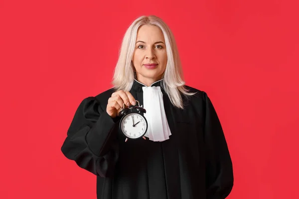 Зрелая Женщина Судья Халате Будильником Красном Фоне — стоковое фото