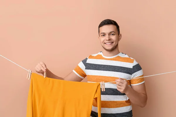 Young Man Hanging Clean Sweater Wooden Clothespin Beige Background — Stock Photo, Image