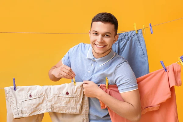Young Man Hanging Clean Shorts Plastic Clothespin Yellow Background — Stock Photo, Image