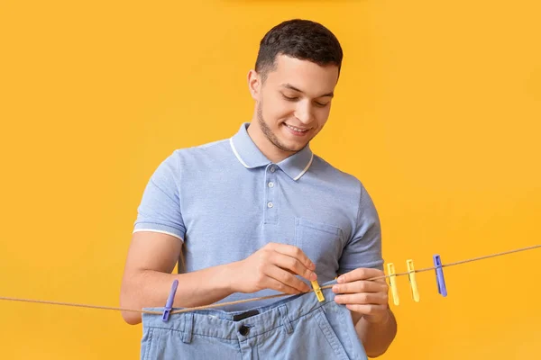 Junger Mann Hängt Saubere Shorts Mit Plastikklammer Auf Gelbem Hintergrund — Stockfoto
