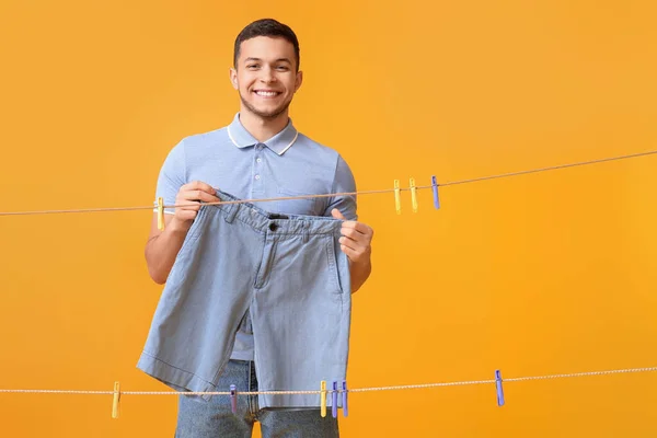 Young Man Hanging Clean Shorts Plastic Clothespin Yellow Background — Stock Photo, Image