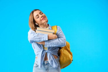 Mavi arkaplan üzerine kitapları olan kız öğrenci