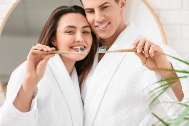 Genç bir çift banyoda aktif kömür diş macunu ile dişlerini fırçalıyor.