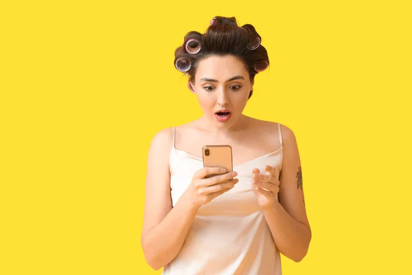 髪のカールと黄色の背景に電話で驚くべき若い女性 — ストック写真