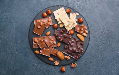 Koyu arkaplanda lezzetli çikolata ve fındık parçaları olan tahta.