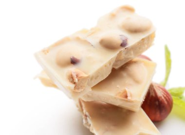 Beyaz arka planda fındıklı lezzetli çikolata parçaları, yakın plan.