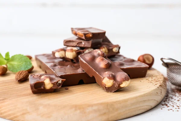 Pieces of tasty chocolate with hazelnuts on board