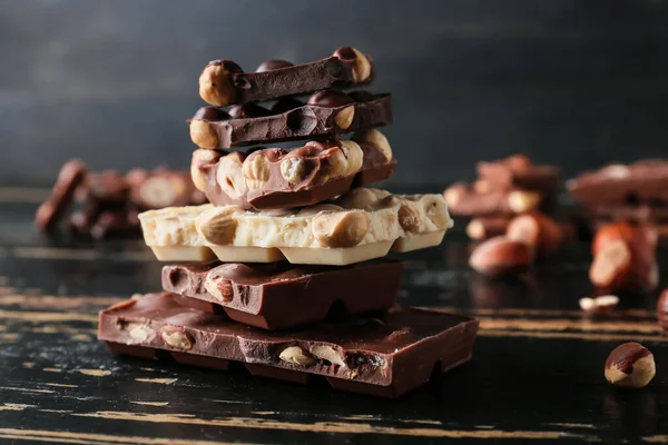 Pieces Tasty Chocolate Hazelnuts Dark Wooden Background — Stock Photo, Image