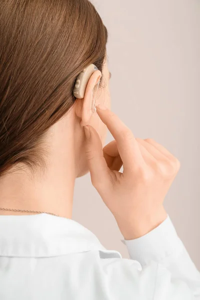 Young Woman Putting Hearing Aid Her Ear Light Background — Stock Photo, Image