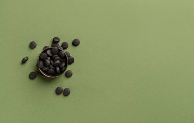 Yeşil arka planda etkinleştirilmiş karbon haplı kase