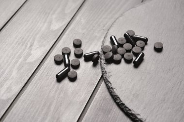 Koyu ahşap arka planda aktif karbon hapları olan tahta