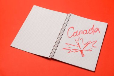 Kelime CANADA ve kırmızı arkaplan üzerine akçaağaç yaprağı çizilmiş defter