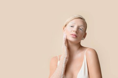 Yaratıcı makyajlı ve parlak arkaplanda zarif eldivenleri olan güzel genç bir kadın.