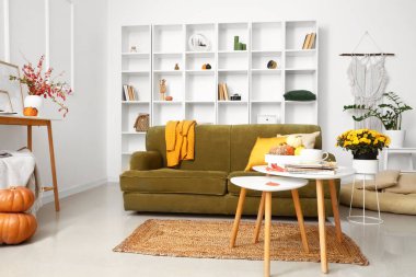 Rahat kanepesi ve kasımpatı çiçekleri olan modern oturma odasının içinde.