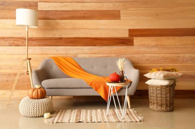 Rahat bir kanepe, masa ve lamba, ahşap duvarın yanında.