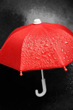 Koyu arkaplanda su damlaları olan kırmızı şemsiye, yakın plan