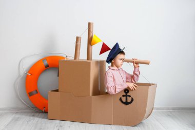 Evde karton gemiyle oynayan komik küçük çocuk.