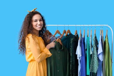 Mezuniyet balosu için mavi arka planda giysileri olan güzel bir Afro-Amerikalı kız.