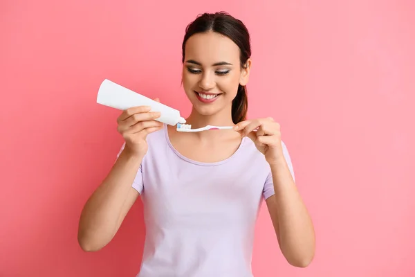 Mladá Žena Použití Zubní Pasty Štětec Růžovém Pozadí — Stock fotografie
