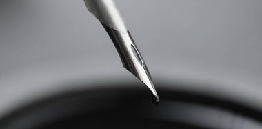 Kalemden siyah mürekkep damlıyor, yakın plan.