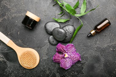 Masaj fırçası ve koyu arkaplanda kozmetik içeren spa kompozisyonu