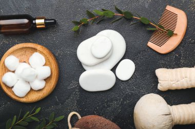 Banyo malzemeleri, bitkisel torbalar ve koyu arkaplanda gerekli yağ içeren spa taşları.