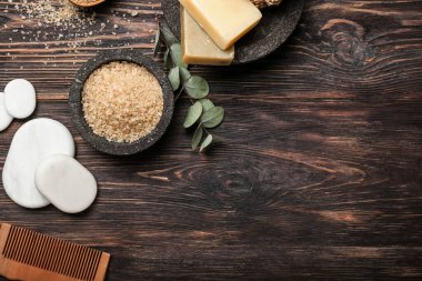 Kaplıca taşlı deniz tuzu ve ahşap zeminde banyo malzemeleri.