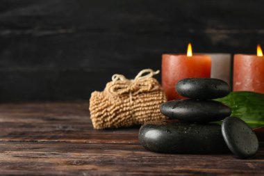 Ahşap masada aroma mumları olan spa taşları.