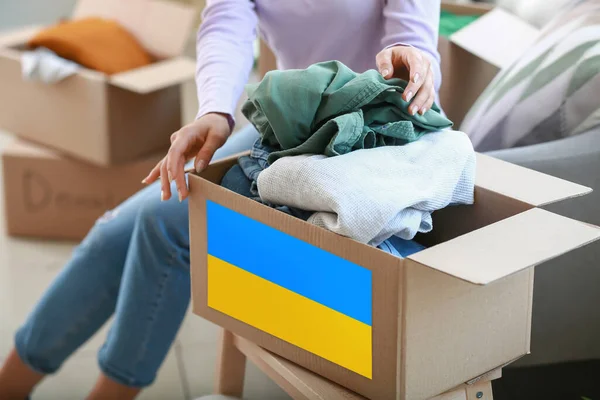 Female volunteer putting clothes in donation box. Humanitarian aid for Ukrainian refugees