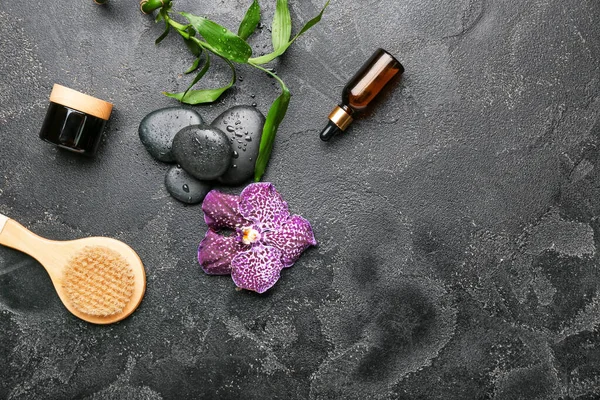 Masaj fırçası ve koyu arkaplanda kozmetik içeren spa kompozisyonu