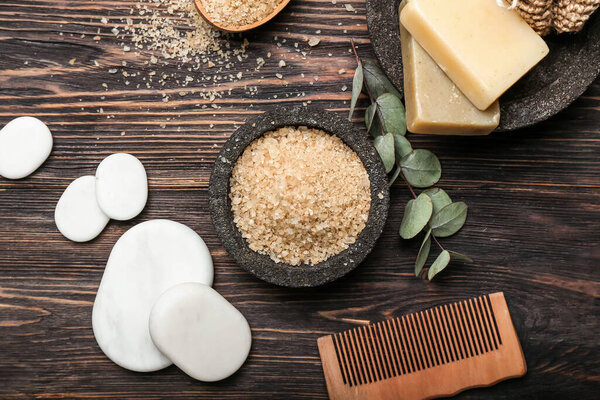 Sea salt with spa stones and bathing supplies on wooden background