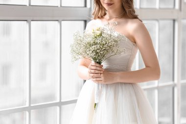 Pencerenin yanında bir buket çiçekli güzel gelin