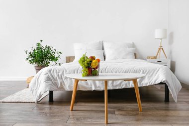 Masa ve meyve sepetli aydınlık yatak odasının içi