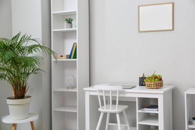 Işık duvarının yanında dizüstü bilgisayarı ve meyve sepeti olan modern işyeri