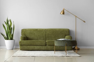 Yeşil kanepe, puf ve lambayla aydınlık oturma odasının içi