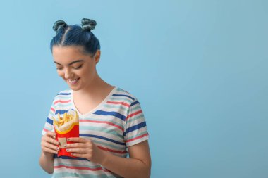 Mavi arka planda patates kızartması olan genç bir kadın.