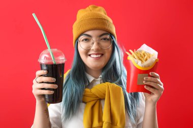 Sıra dışı saçları olan genç bir kadın kola ve patates kızartması tutuyor.