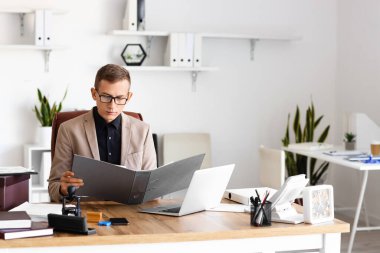 Genç erkek noter ofiste çalışıyor.