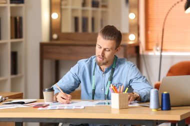 Stüdyoda çalışan genç erkek giyim tasarımcısı.