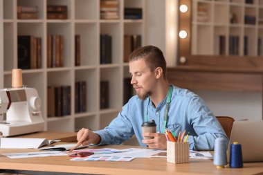 Stüdyoda çalışan genç erkek giyim tasarımcısı.