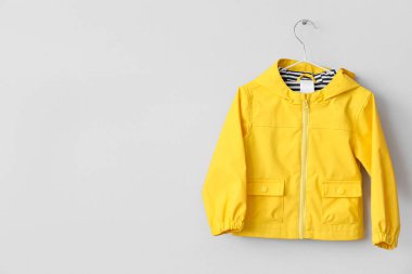 Sarı çocuk yağmurluğu duvarda asılı.