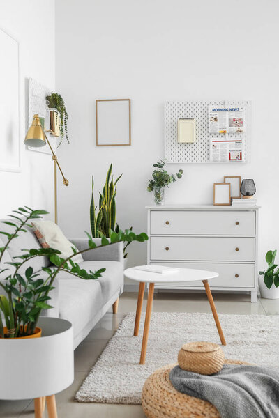 Interior of light living room with sofa and hanging peg boards